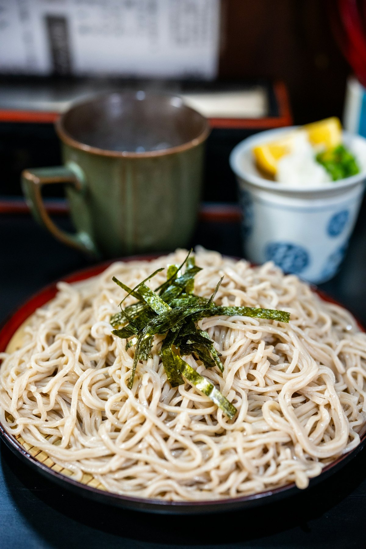 ざるに盛った十割せいろ。刻み海苔をひとつまみ、脇に薬味と湯呑み。